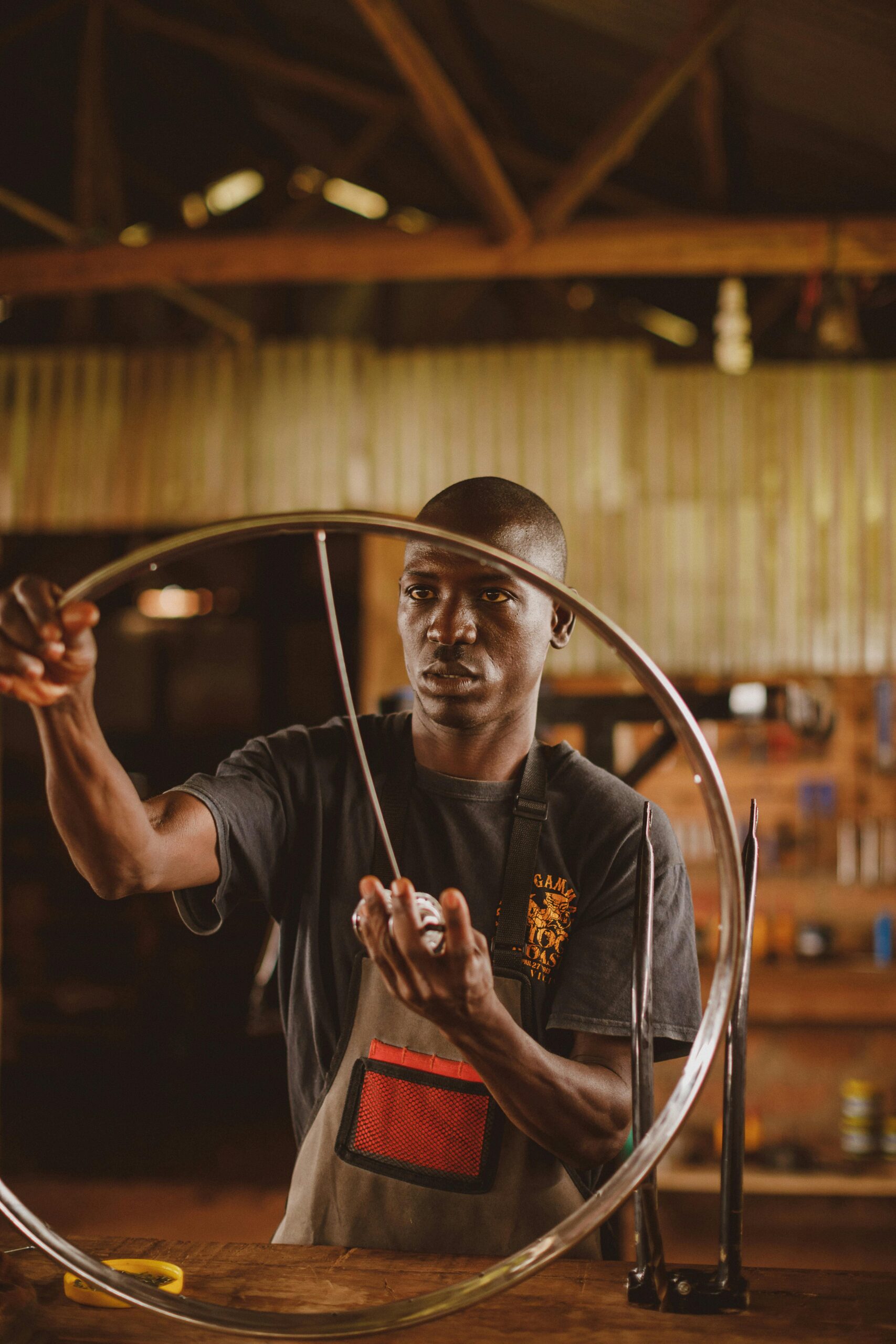 African mechanic working with a bicycle wheel in a workshop in Gayaza, Uganda.